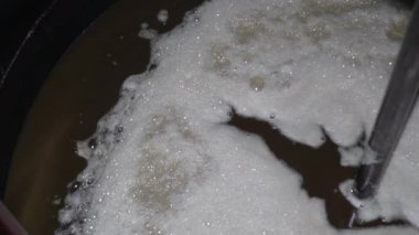 Taze sıkılmış ayçiçeği yağı ve kabın içinde dönen beyaz köpük. Ay çekirdeği veya yağ çekirdeği sıktıktan sonra yağlı kahverengi sıvı. Petrol çıkarmak için endüstriyel üretim. Kapatın. Yavaş çekim