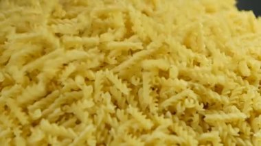 Kuru makarna yığınının üstüne sarmal makarna dökülüyor. Fabrikada İtalyan makarnası üretimi. Undan ya da buğdaydan yapılan sağlıklı yiyeceklerin geçmişi. Reklam ve pazarlama için uygun.