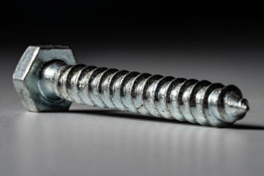 Gri siyah arka planda altıgen başlı metal spiral vida. Sarmal paslanmaz çelik cıvata. Marangozluk ya da onarım için tamir aleti. Düzüşmek ya da bağlamak için spiral çapa. Mettalik yapı