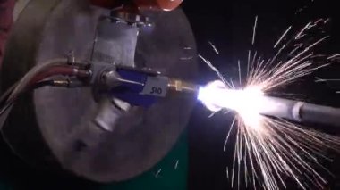 Termal sprey metal kaplama işlemi. Metalurjik bir tesiste barut alevi püskürtme işlemi sırasında çeliği döndürmek. Otomatik endüstriyel robot kaynak makinesi. Uçan kıvılcımlı plazma kaynağı