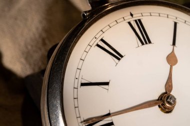 Elleri ve Roma rakamları olan antik bir gümüş cep saatinin telefon numarası. Beyaz kadranlı yuvarlak bir retro saati kapat. Şatafatlı yaşlandırılmış saat. Mekanik eski metal saat