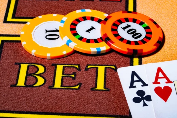 Kumarhanedeki oyun masasında kağıt ve fiş. İki as ve 100 dolar değerinde kumarhane fişi. Poker, briç ya da blackjack oynamaya hazırız. Kumarhanede kumar oynamış. Ekstra yakın çekim