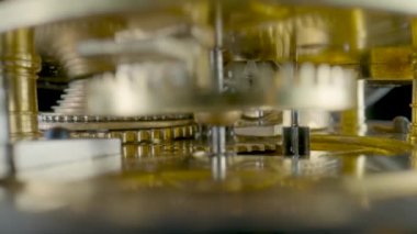 Inside view of moving clockwork of golden mechanical clock. Rotating gold gears, gearing, wheel with toothed. Disassembled watch with cogwheel and spring. Macro shot of turning watch mechanism parts