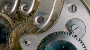 İçsel saat mekanizması makro. Dönen altın dişliler, metal dişliler, dişli tekerlekler. Vidaları, çarkları ve yayı olan parçalanmış bir saat. Eski tip saat mekanizması çalışıyor