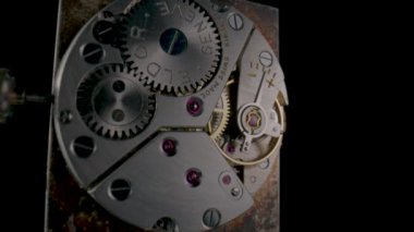 Disassembled vintage pocket watch with clockwork turning on black isolated background. Working clock mechanism with rotating spring, gears, gearing and toothed wheels. Inside view of a moving