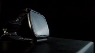 Old black wrist watch with handmade leather wristlet rotating on black isolated background. Stopped hand watch with dial, hands and numbers. Retro gdr clock with watchstrap in dark. Close up