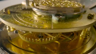 Inside view of moving clockwork of golden mechanical clock. Rotating gold gears, gearing, wheel with toothed. Disassembled watch with cogwheel and spring. Macro shot of turning watch mechanism parts