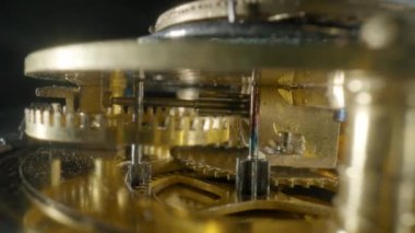 Siyah izole edilmiş stüdyo arkaplanındaki altın mekanik saatin hareketli bir iç görünümü. Dönen altın dişliler, dişliler, dişli tekerlekler. Çarklı ve yaylı parçalanmış saat. Makro