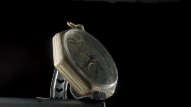 Siyah izole edilmiş arka planda dönen bir standın üzerindeki altın antika cep saati. Beyaz kadranlı yuvarlak altın retro saat, eller ve numaralar. Eski model mekanik cep saati. Kapat.