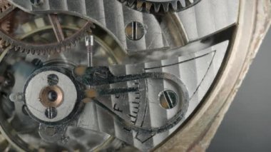 İç klasik saat mekanizması makrosu. Dönen gümüş dişliler, metal dişliler, dişlilerin tekerlekleri. Vidaları, çarkları ve yayı olan parçalanmış bir saat. Çalışan saat ve parçalarını aç