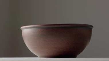 Boş toprak tabakası koyu gri arka planda dönüyor. Kahverengi el yapımı ramekin. Boş toprak eşyalar, yiyecek için kilden çanak çömlek. Eski kalın tabaklar yuvarlak