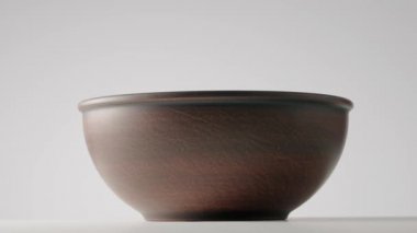 Boş toprak derin kase açık gri stüdyo arka planında dönüyor. Kahverengi el yapımı ramekin. Boş toprak eşyalar, yiyecek için kilden çanak çömlek. Eski kalın tabaklar yuvarlak