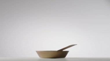 Copper fryingpan spinning on on a light gray studio background. Round empty stainless or aluminum pan with handle. Kitchenware, utensils for cooking and frying, interior decoration