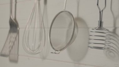 Spatula, çırpıcı, ezici ve süzgeç restoran veya ev mutfağında ahşap duvarda asılı duruyor. Mutfak aletleri paslanmaz çelikten ya da metalden yapılmış. Yemek pişirmek için gerekli aletler.