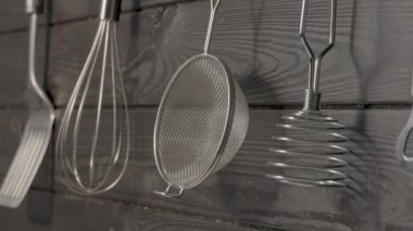 Spatula, çırpı, ezici ve süzgeç restoranda ya da ev mutfağında ahşap duvarda asılı duruyor. Mutfak aletleri paslanmaz çelikten ya da metalden yapılmış. Yemek pişirmek için gerekli aletler. Mutfak eşyaları.