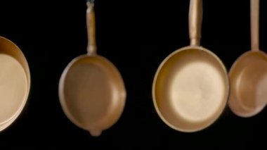 Kırsal bakır kızartma tavalarını izole edilmiş siyah stüdyo arka planına as. Dolu boş altın tavaları ve sapları. Mutfak eşyaları, yemek ve kızartma için mutfak gereçleri. Restoranın iç mimarisi