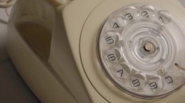 Bir adamın eli ahizeyi kaldırıyor ve tuşlayıcıyı parmağıyla çeviriyor. Disk kadranlı eski bir telefon üzerinde telefon numarası çeviren bir erkek parmak. Retro plastik telefon. Konsept: