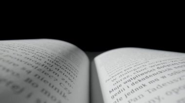Beyaz sayfa ve siyah izole edilmiş stüdyo arkaplanı üzerine uzanan metin içeren açık bir kitap. Harfli ders kağıtları. Öğrenme, bilgi edinme, okulda, üniversitede ya da üniversitede eğitim. Okunuyor