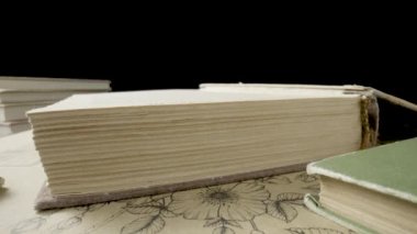 Siyah stüdyo arka planında boş beyaz sayfaları olan açık bir kitap. Kütüphanedeki masanın üzerinde pejmürde kapaklı eski kitaplar vardı. Klasik ders kitapları. Eski edebiyat, yayınlar. Kapat.