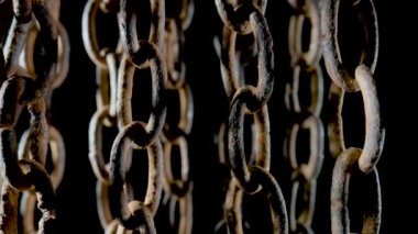 Old metal chain with dark rusted links on black isolated studio background. Rusty hanging aged chain in dust and dirt. Structure of the metal covered with corrosion. Light and shadow. Rough metal