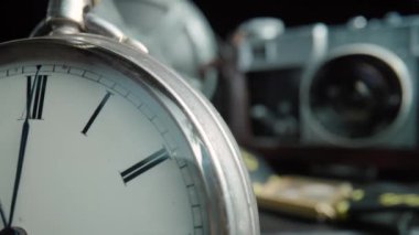 Antique silver dial of pocket watch, camera, wristwatch and vintage film reel on black isolated background. Retro pocket watch with hands and Roman numerals. Vintage objects are laid out on dark
