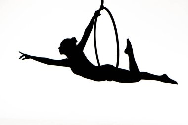 Black silhouette of a young woman posing on an air ring on an isolated white studio background. Female aerial acrobat performs tricks and balances on aerial hoop. Circus acrobatic show. Equilibrist