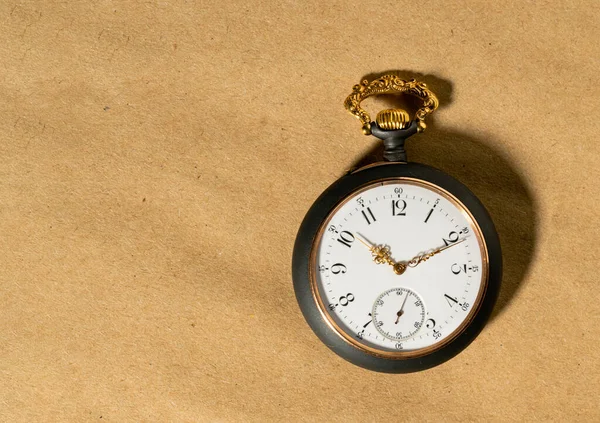 Gray vintage pocket watch with gold hands on a round dial. Old retro clock on a beige background with place for advertising or text, mockup for presentation of watch shop . Concept of time, past