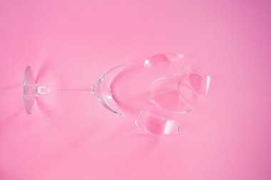 Broken champagne glass with splinters on pink background. Wineglass fallen and shattered into smithereens with sharp glass edges. Concept fight against alcoholism, drunkenness and refusal of alcohol