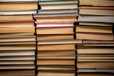 Shelves with old books. Stacks of textbooks with red, blue, green covers and paper sheets with shadow in a dark library. Stacked retro books in a bookstore