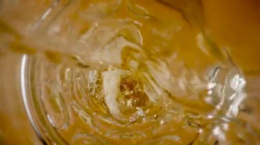 Kehribar sıvısı bardağa dökülüyor. Altın bira, elma şarabı ya da lagarın dökülmesi, köpük oluşumu ve küçük kabarcıklar. Sarı yağ akışı. Köpüklü karbonatlı içecek bardağa dökülür.