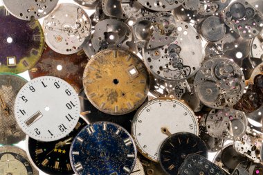 Eski saatlerin göstergelerinin ve saatlerin üst görüntüsü. Beyaz, siyah ve metal saatlerin ve dişli gümüş iç mekanizmanın yüzleri. Kırık ya da parçalanmış saatlerin eski paslı parçaları.