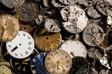 Eski saatlerin göstergelerinin ve saatlerin üst görüntüsü. Beyaz, siyah ve metal saatlerin ve dişli gümüş iç mekanizmanın yüzleri. Kırık ya da parçalanmış saatlerin eski paslı parçaları.