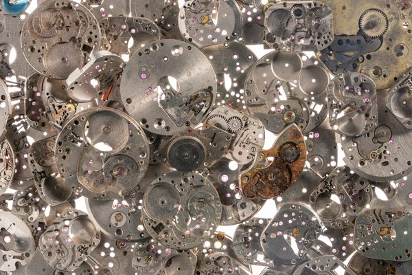 Beyaz ışık arka planında eski bir saatin metal iç parçalarının üst görüntüsü. Dişli ve dişli gümüş saat mekanizması. Paslı antika saat parçaları. Parçalanmış saat antika mekanizması