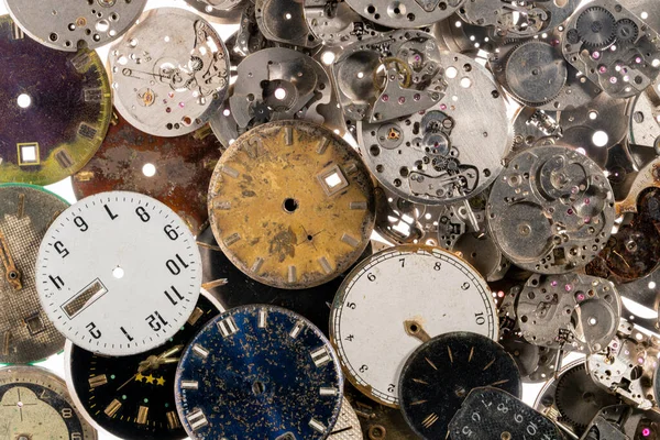 Eski saatlerin göstergelerinin ve saatlerin üst görüntüsü. Beyaz, siyah ve metal saatlerin ve dişli gümüş iç mekanizmanın yüzleri. Kırık ya da parçalanmış saatlerin eski paslı parçaları.