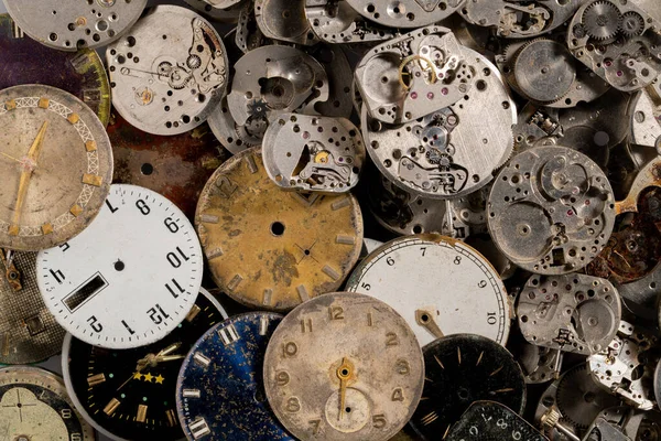 Eski saatlerin göstergelerinin ve saatlerin üst görüntüsü. Beyaz, siyah ve metal saatlerin ve dişli gümüş iç mekanizmanın yüzleri. Kırık ya da parçalanmış saatlerin eski paslı parçaları.