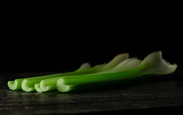 Row Green Celery Stalks Lying Black Board Isolated Black Studio — Stock Photo, Image