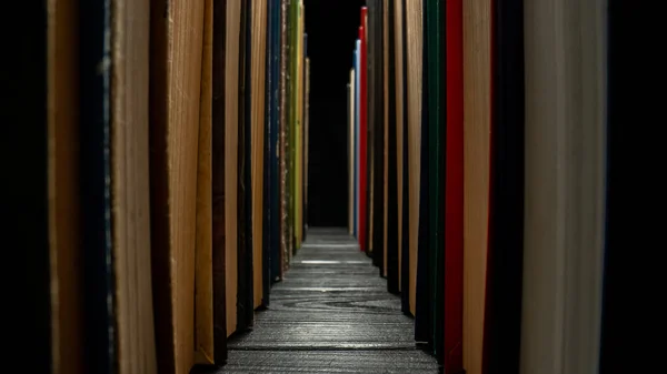 图书馆的书架上排列着一排排有色封面的书 绿色和蓝色封面的旧书 背景是孤立的黑色 古代文学 供学习用的教科书 成排排列 — 图库照片