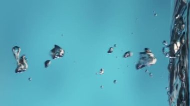 Suyun sakin yüzeyinde yükselen ve patlayan parlak hava kabarcıkları. Kaplara dökülen temiz mavi sıvının tazeliği. Şeffaf mavi su ve ışık parlaması. Sıvının çekimini kapat