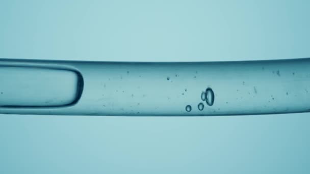 透明的玻璃管 透明的水和空气在蓝色背景的气泡流动 宏观拍摄的流动的液体物质与泡沫的形成 化学或生物概念 — 图库视频影像