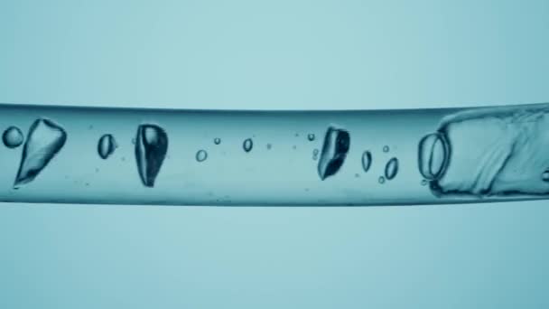 不同尺寸的透明气泡在蓝色背景液体的玻璃管中流动的宏观镜头 具有清晰液体物质和流动气泡的容器 化学或生物研究的概念 — 图库视频影像