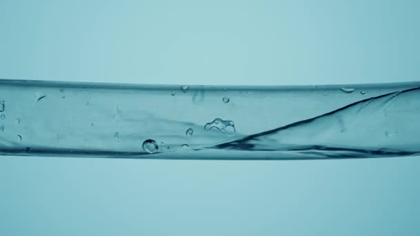 水流进透明玻璃管的内部 呈蓝色的孤立背景 清澈的液体充满管子 形成小气泡 实验室研究 化学实验 化妆品 — 图库视频影像