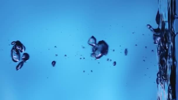 新的空气气泡在平静的水面上升起并破裂 清澈的蓝色液体倒入容器中 透明的蓝色水族箱 闪烁着光芒 近距离拍摄液体 — 图库视频影像