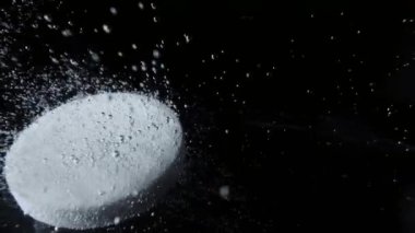 Makro yuvarlak beyaz tablet çözünür aspirin, koyu arkaplanda bir bardak suda fokurduyor. Asetilsalik asit tableti suda çözünür ve birçok tıslama kabarcığı oluşturur. Baş ağrısı