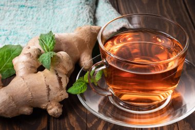 Zencefil çayı, nane yaprağı ve zencefil kökü ahşap arka plan.