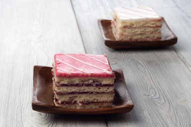 Beyaz ahşap arka planda pembe süslemeli ve beyaz süslemeli kek.