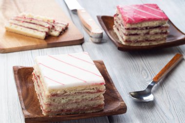 Beyaz ahşap arka planda pembe süslemeli ve beyaz süslemeli kek.