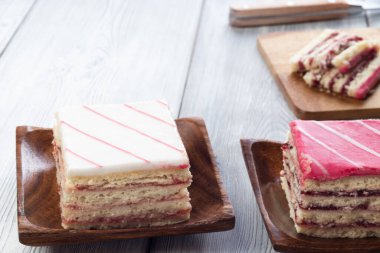 Beyaz ahşap arka planda pembe süslemeli ve beyaz süslemeli kek.