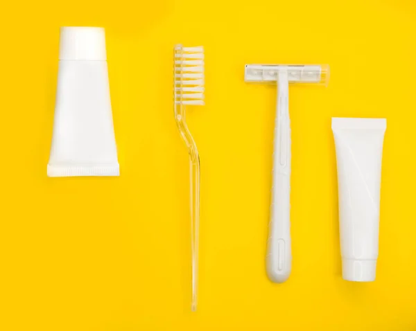 Cepillo de dientes, afeitadora, pasta de dientes, fondo amarillo minimalista. —  Fotos de Stock