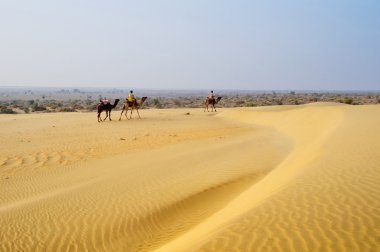 kum tepeleri üzerinde geçmekte deve