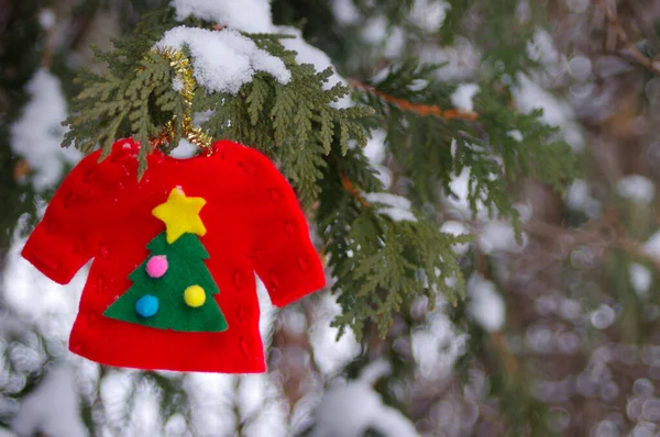 コピースペースと雪に覆われた木にぶら下がっ醜いクリスマスセーターの飾り — ストック写真